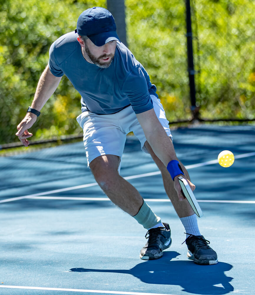 Pickleball player bends low