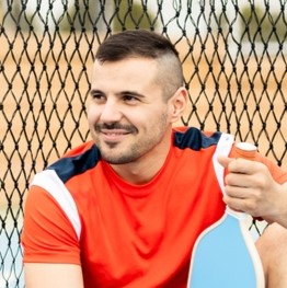 Sid Edmondson with blue paddle in pickleball yard