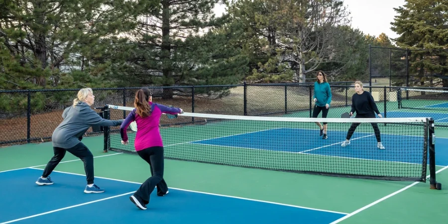 four women pickleball players volley