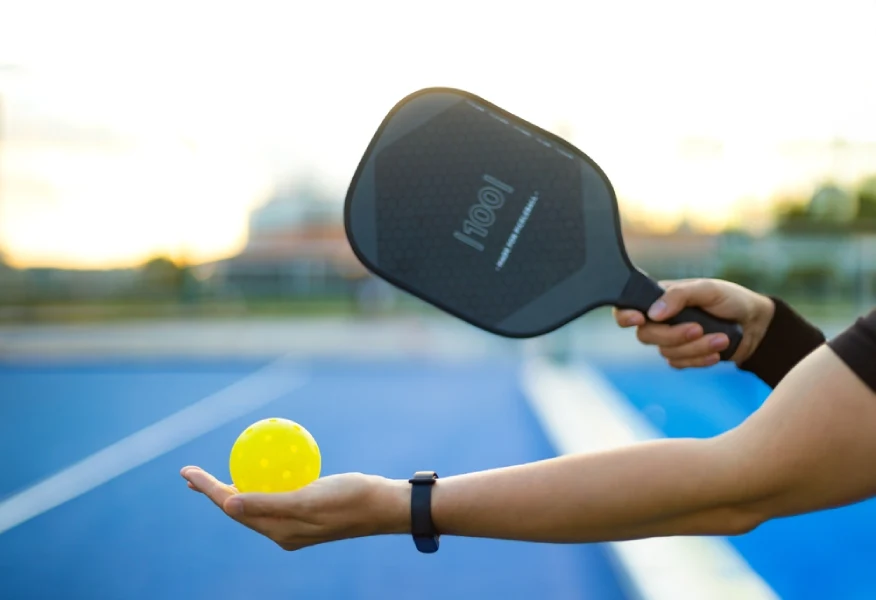 pickleball player holding a fiberglass paddle with pickleball ball