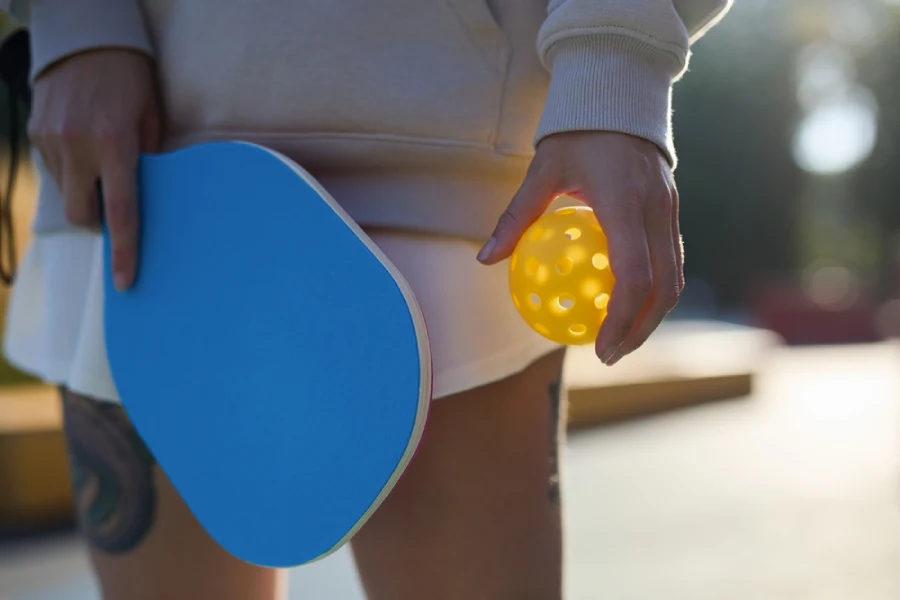 a girl hold lightweight pickleball paddle and yellow ball