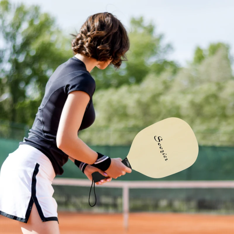 a woman player holding wood pickleball paddle