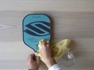 clean surface pickleball paddle with warm water and cloth