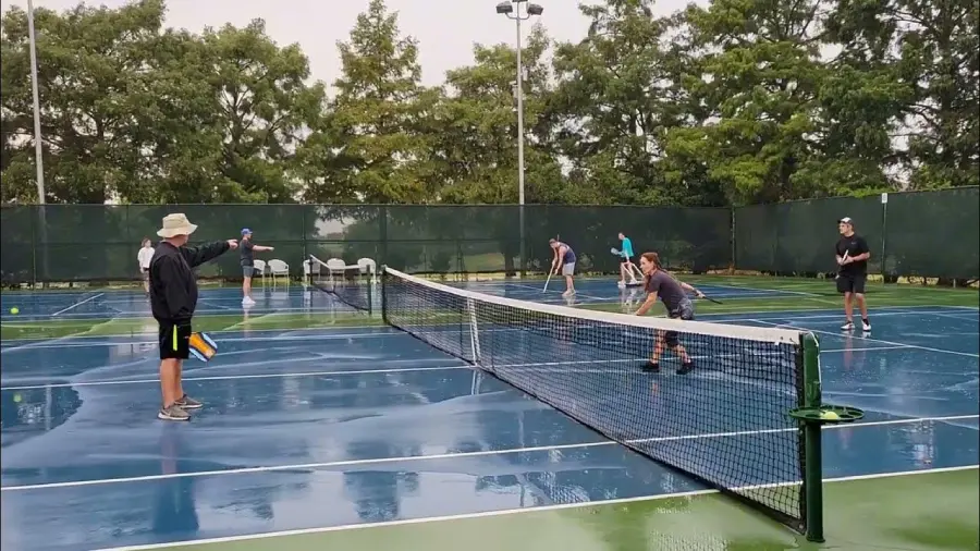 a group of player stands in wet pickleball court