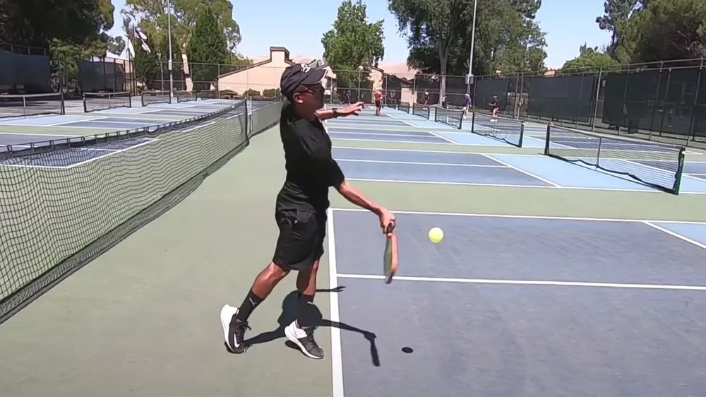 Player focuses on executing a precise serve during a pickleball match, setting up the play with a strong start.